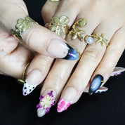 Almond press-on nails in black and purple with vibrant 3D floral designs, perfect for a bold, edgy style.