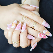 Soft pink and yellow almond press-on nails with delicate 3D floral designs and butterfly accents, elegant and feminine style.