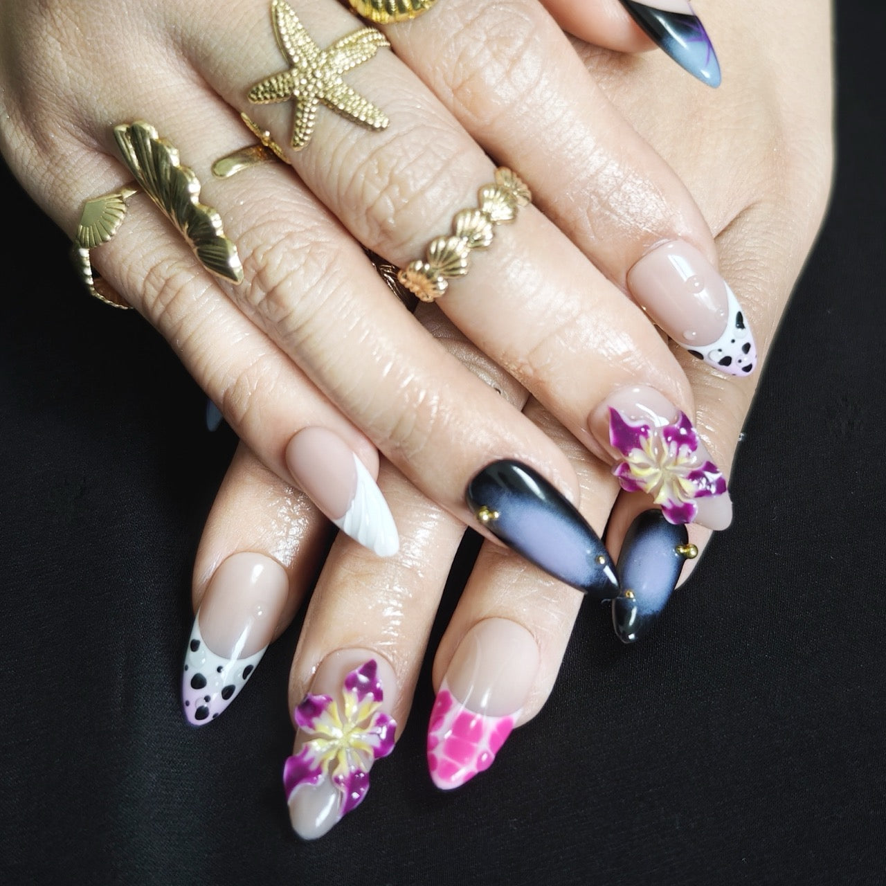 Almond press-on nails in black and purple with vibrant 3D floral designs, perfect for a bold, edgy style.