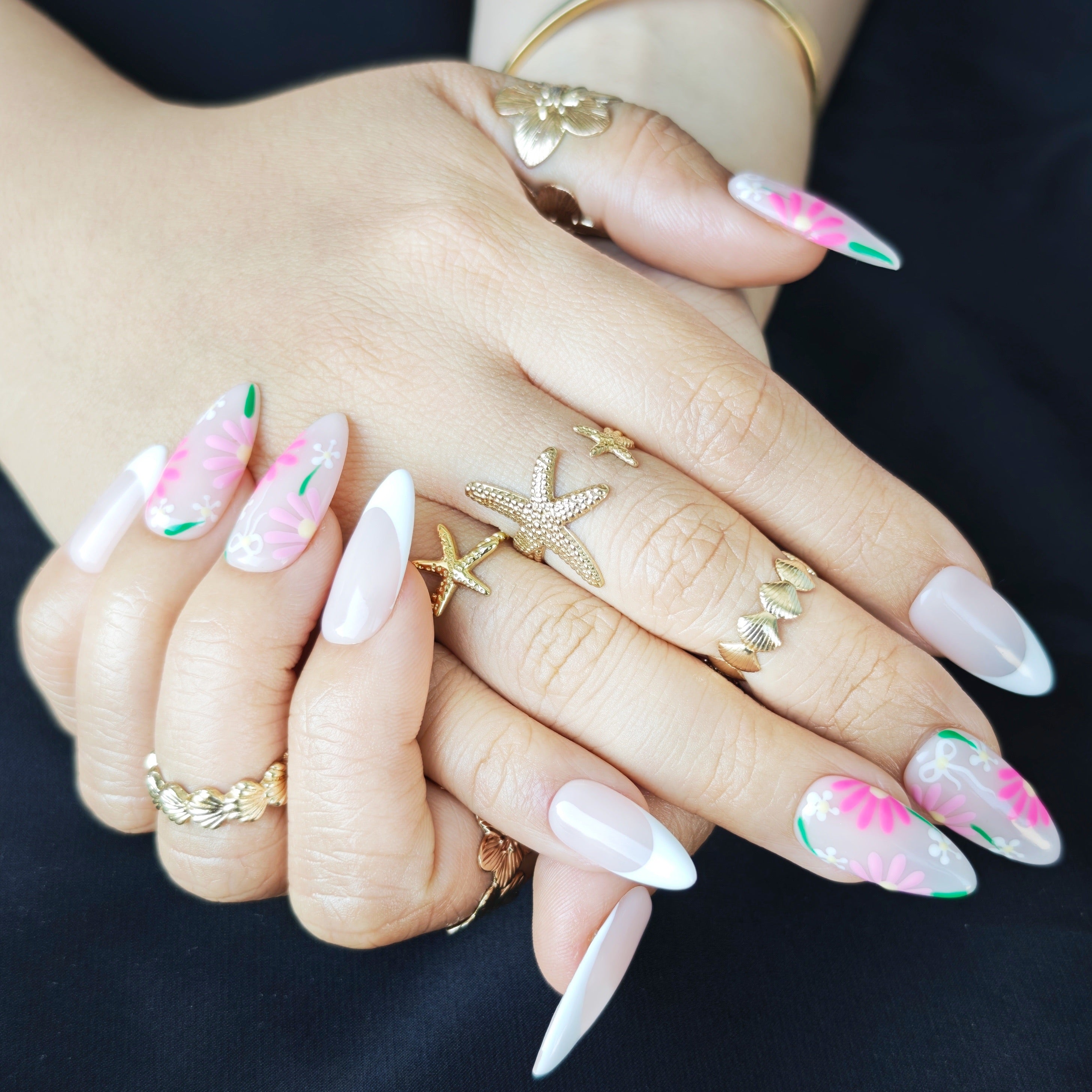 French-style almond press-on nails in white and pink with small floral designs, creating a soft spring-inspired look.