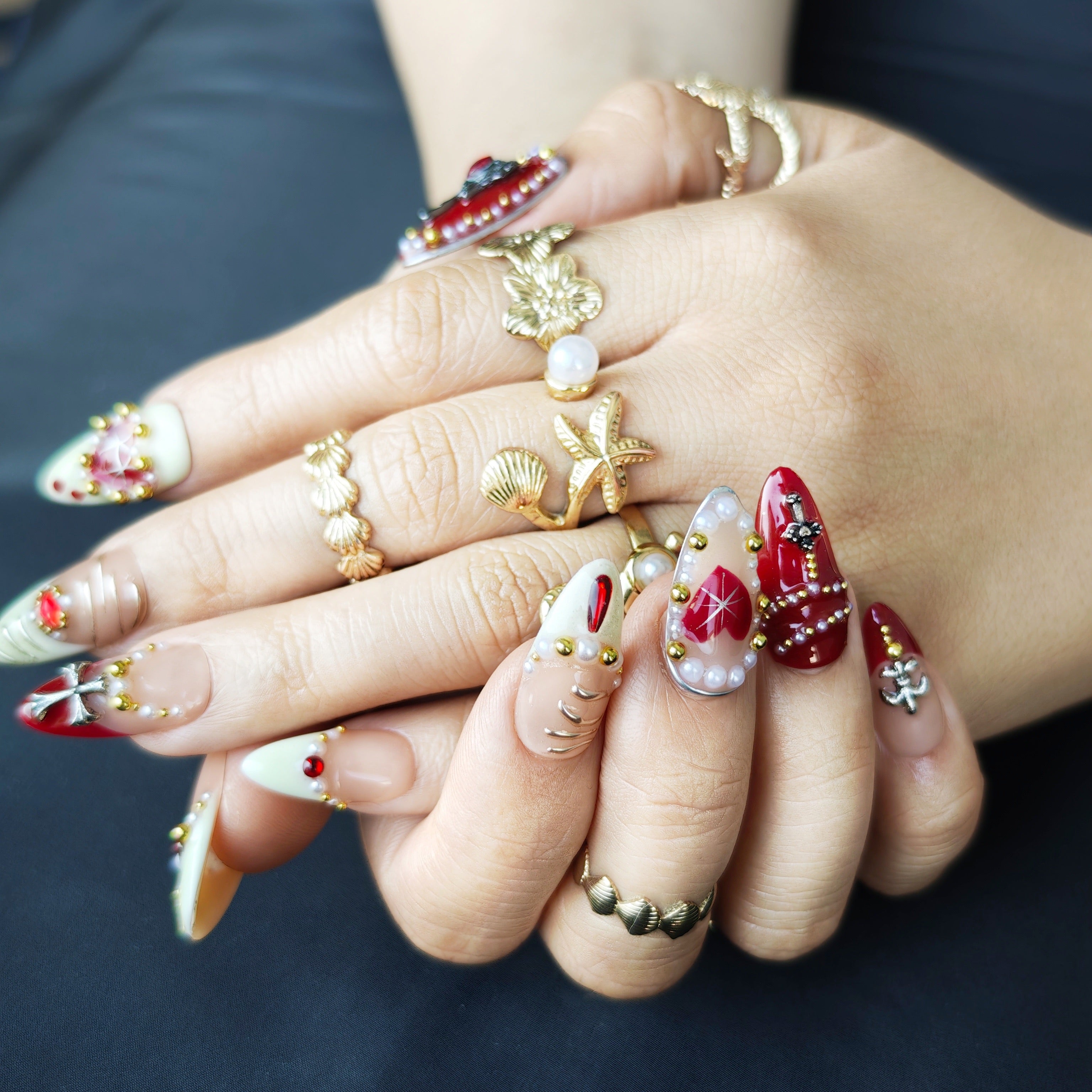Hand wearing Pearl Ruby gothic almond press-on nails with vintage dark feminine nail art style