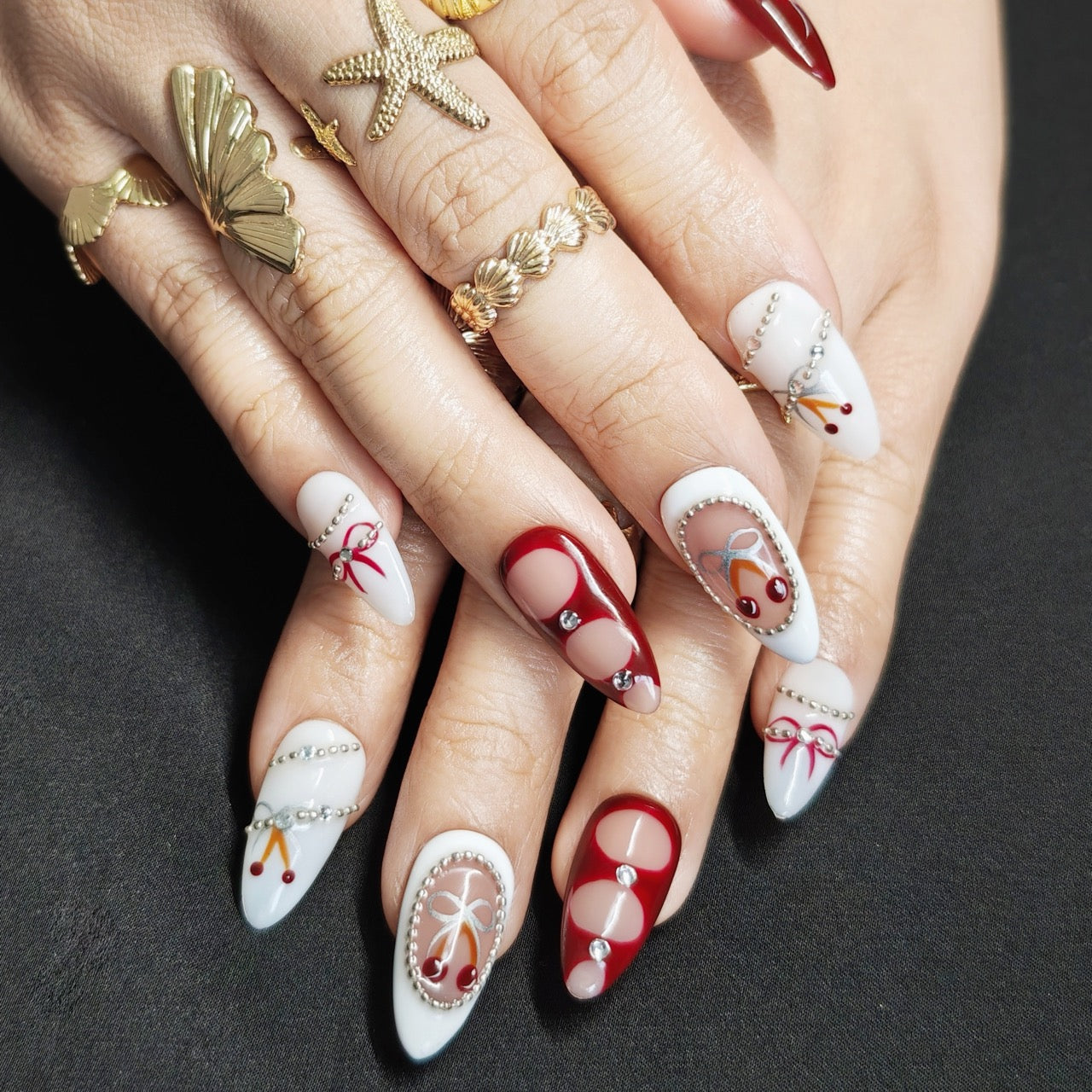 White and red almond press-on nails with hand-painted cherry and silver pearl accents, luxurious festive winter design.
