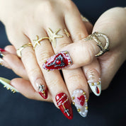 White and red almond press-on nails with intricate handcrafted 3D details, gold beads, pearls, and ruby rhinestone accents.