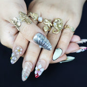 Handcrafted almond press-on nails in silver with 3D shell and cherry floral designs, luxurious and detailed.