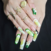 Woman wearing Cool Jungle tapered square press-on nails with forest green gradients, floral details, and elegant botanical manicure style
