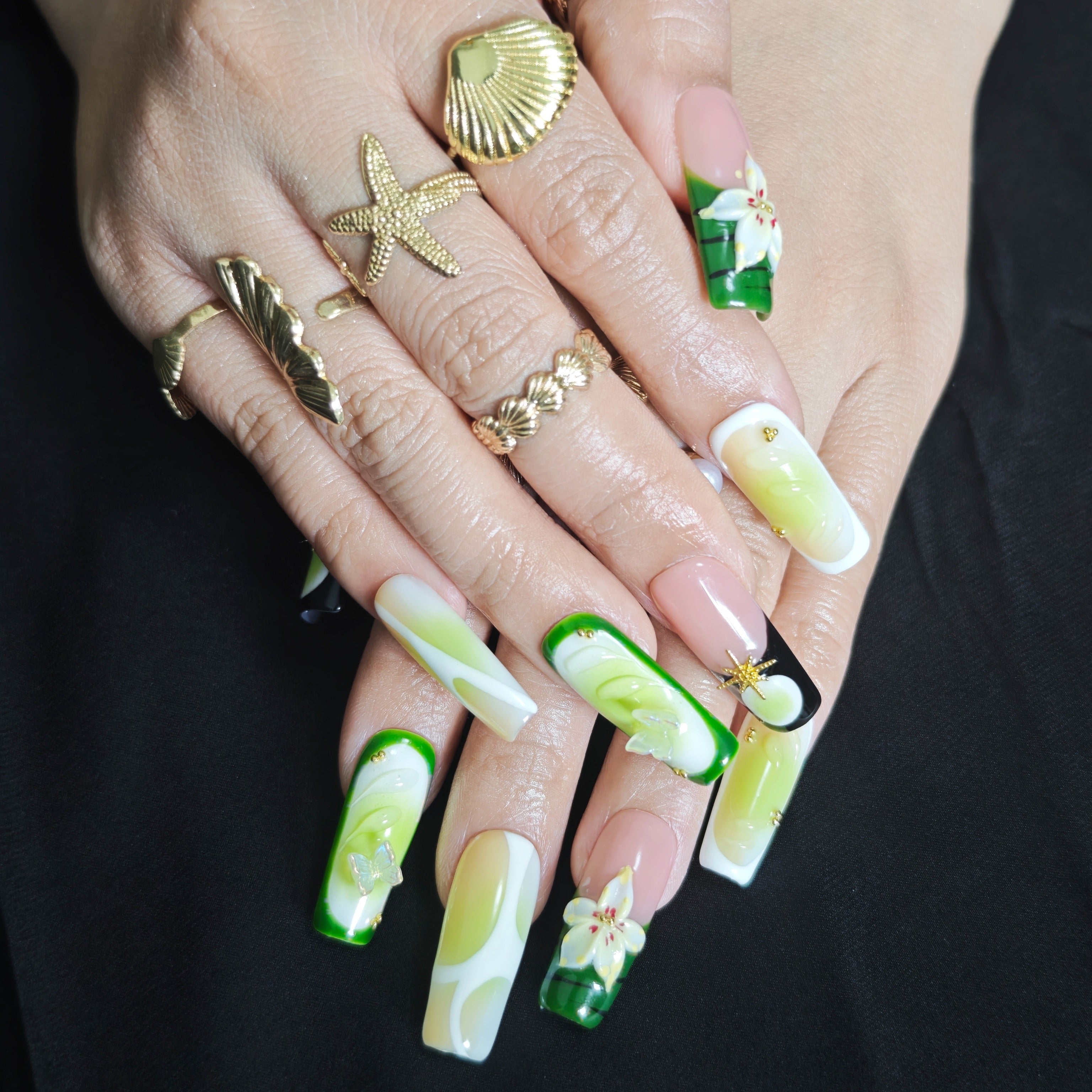 Woman wearing Cool Jungle tapered square press-on nails with forest green gradients, floral details, and elegant botanical manicure style