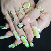 Close-up of Cool Jungle handmade press-on nails showing 3D white lily flowers, transparent butterfly decorations, gold accents, and watercolor green nail art