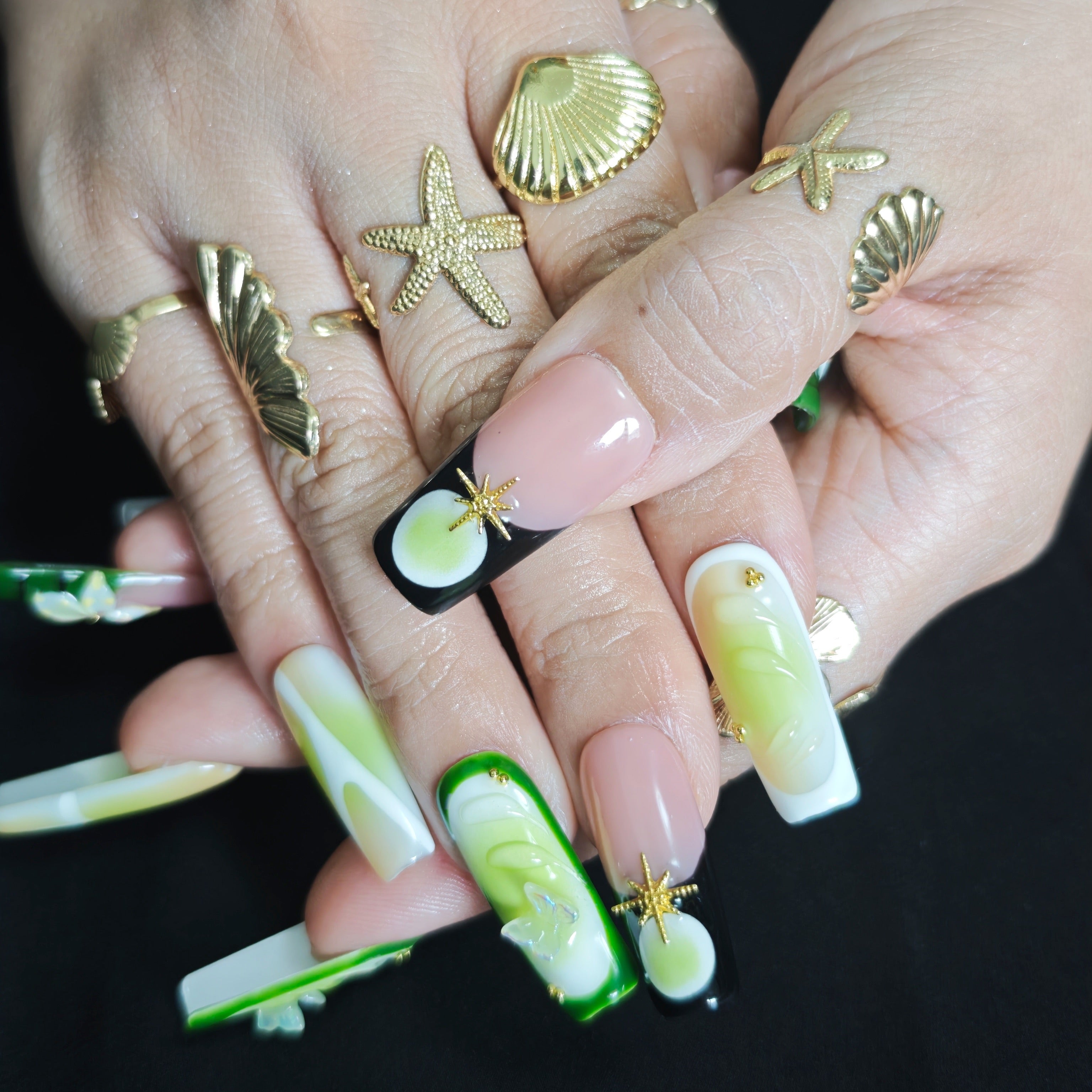 Close-up of Cool Jungle handmade press-on nails showing 3D white lily flowers, transparent butterfly decorations, gold accents, and watercolor green nail art