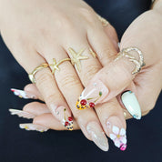 Handcrafted almond press-on nails in silver with 3D shell and cherry floral designs, luxurious and detailed.