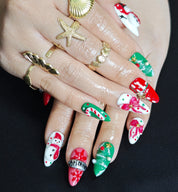 Almond press-on nails with two 3D snowmen, a Christmas tree, and bow in red, green, and white for festive holiday look.