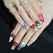 Long square press-on nails with 3D candy, snowman, Santa, and bow decorations in red, green, and white for festive Christmas look.