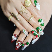 Red and green almond press-on nails with 3D Santa, Christmas tree, and wreath designs for festive holiday style.