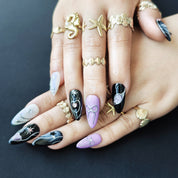 Hand wearing Midnight Rose almond press-on nails with black floral nail art and sweet cool gothic style