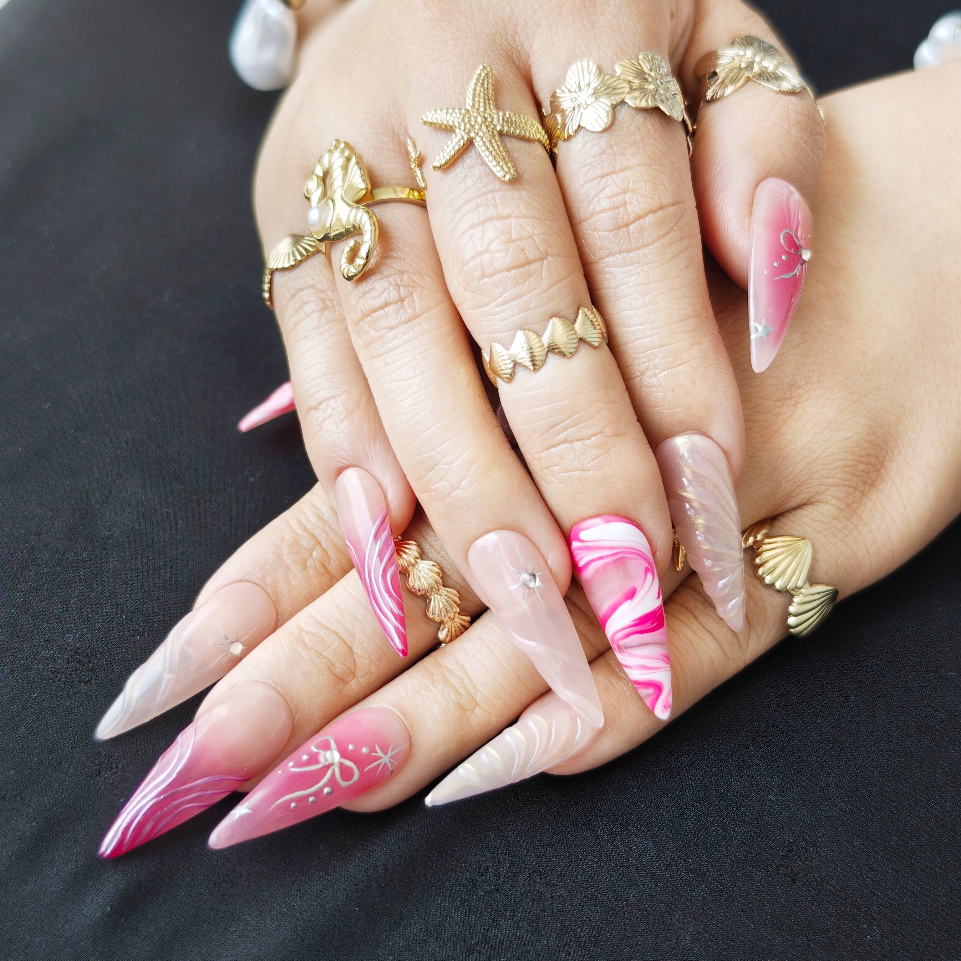 Woman wearing Pink Riot stiletto press-on nails with pink marble patterns, Y2K inspired details, and bold sweet cool girl manicure style