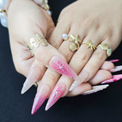 Close-up of Pink Riot handmade press-on nails showing pink fluid marble textures, spiral 3D details, white bows, stars, and crystal decorations