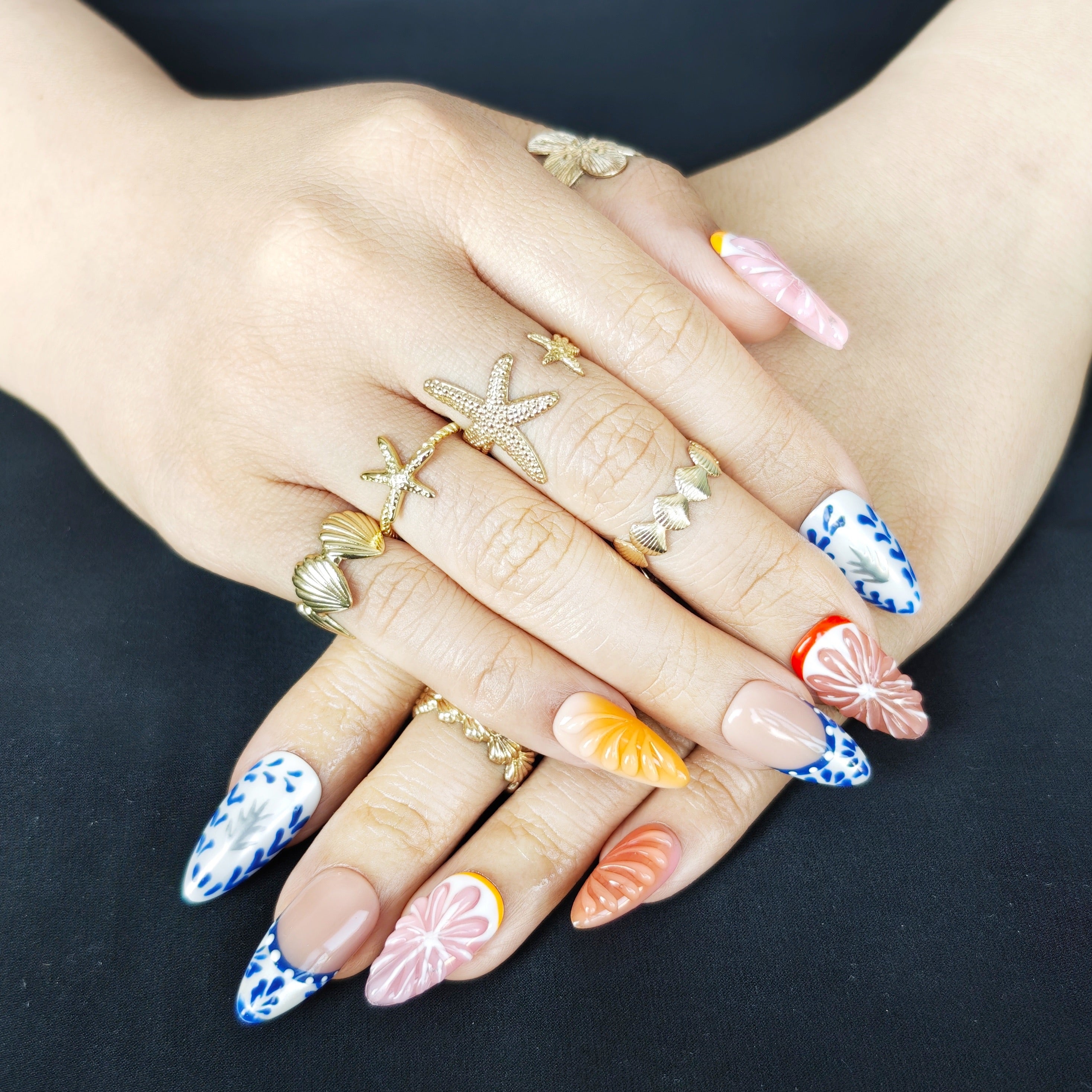 Woman wearing Orange Zest 3D orange almond press-on nails with Mediterranean ceramic patterns for a fresh summer vacation manicure