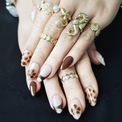 Mocha and brown short almond French press-on nails with white floral accents, designed for a cozy winter aesthetic.