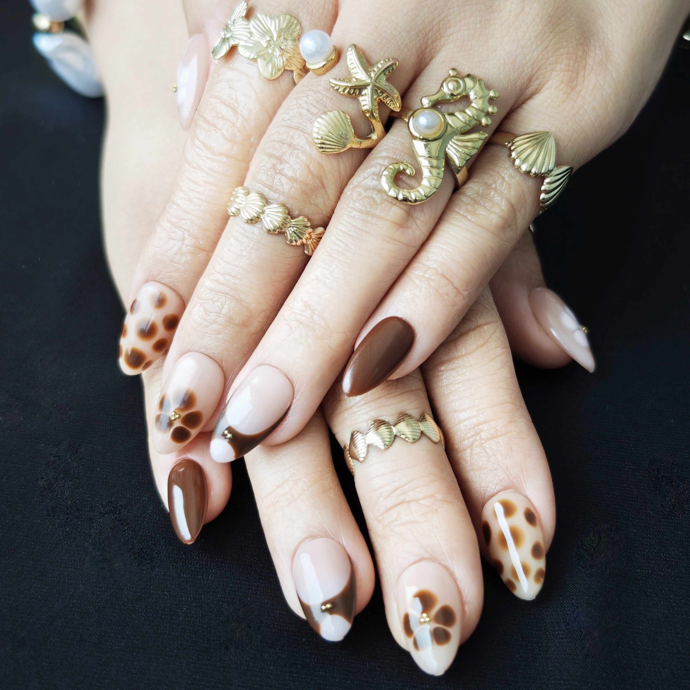 Mocha and brown short almond French press-on nails with white floral accents, designed for a cozy winter aesthetic.