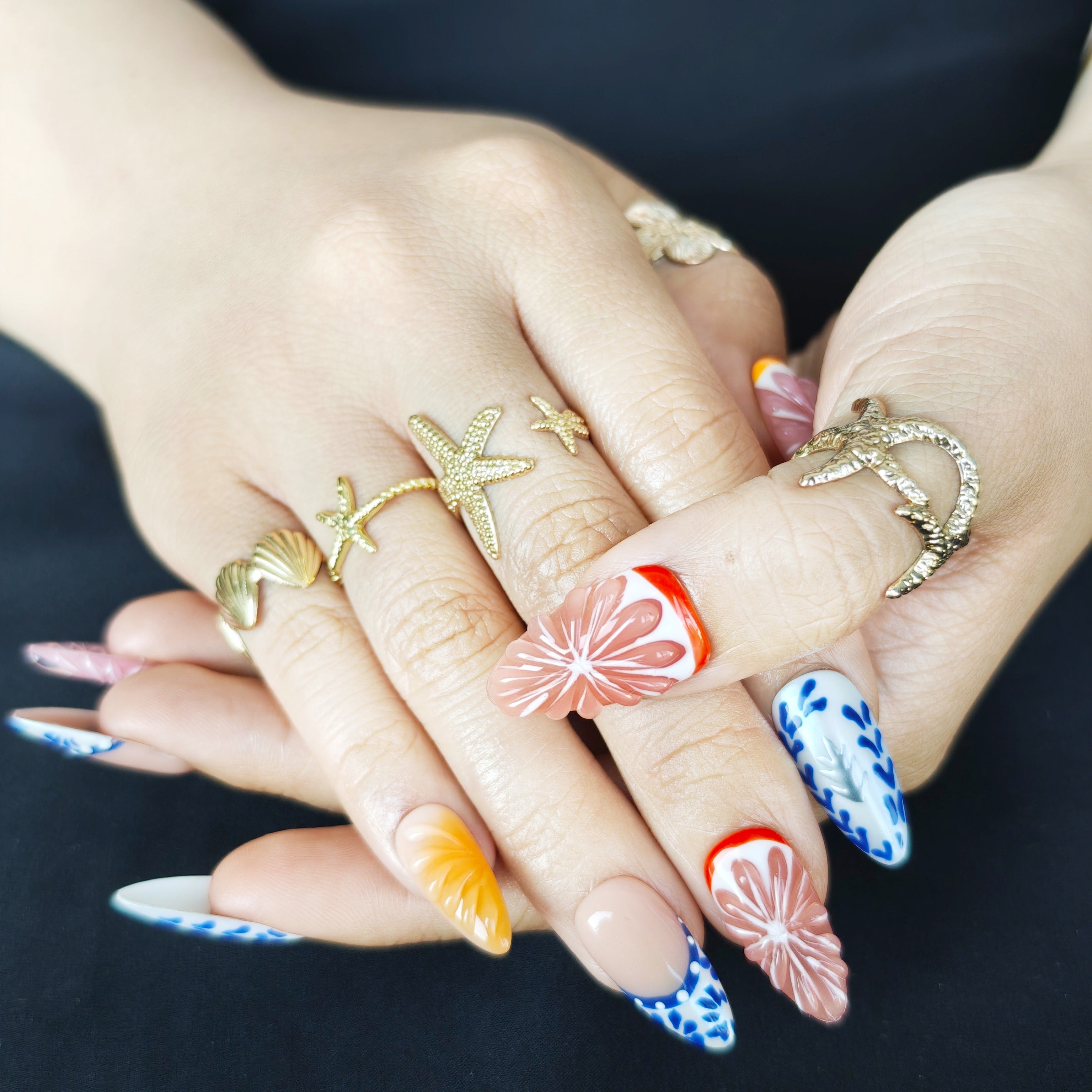 Close-up of Orange Zest handmade press-on nails showing realistic 3D orange fruit details and blue white ceramic nail art design