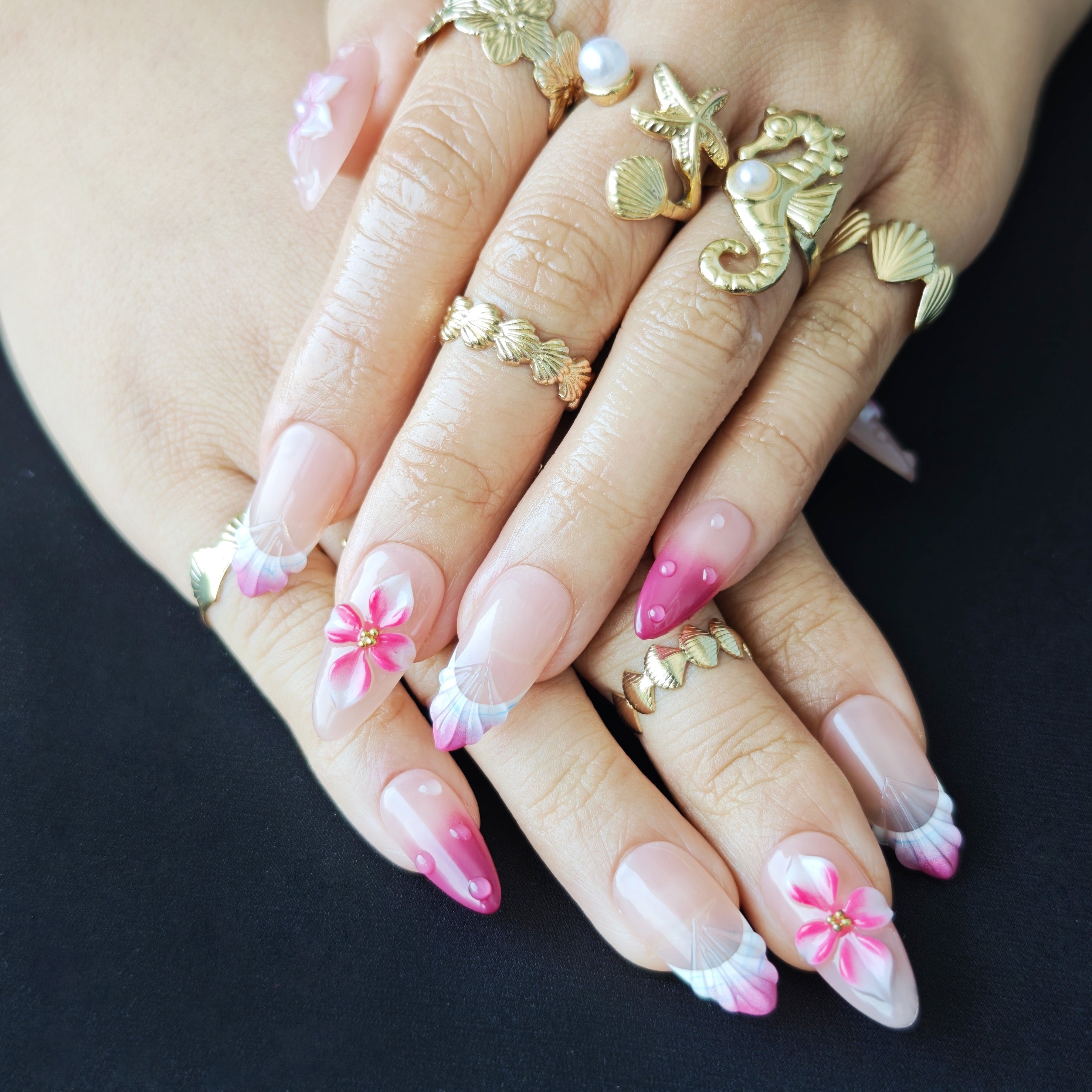 Woman wearing Fairy Pink 3D flower almond press-on nails with soft pink gradient, ocean inspired details, and elegant summer manicure style