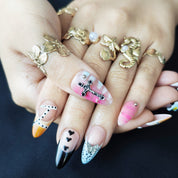 Almond press-on nails in yellow with pink cross, blue floral accents, and silver butterfly decorations.
