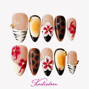 Black animal print and zebra stripe almond press-on nails with gold bead accents and two handmade 3D flowers.