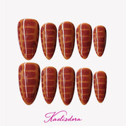 Almond-shaped press-on nails with caramel ombre and subtle snake pattern for minimalist luxury style.